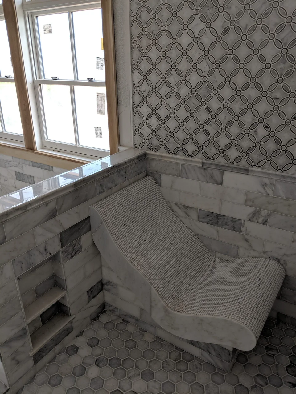 Hand-finished curved mosaic bench and patterned shower walls