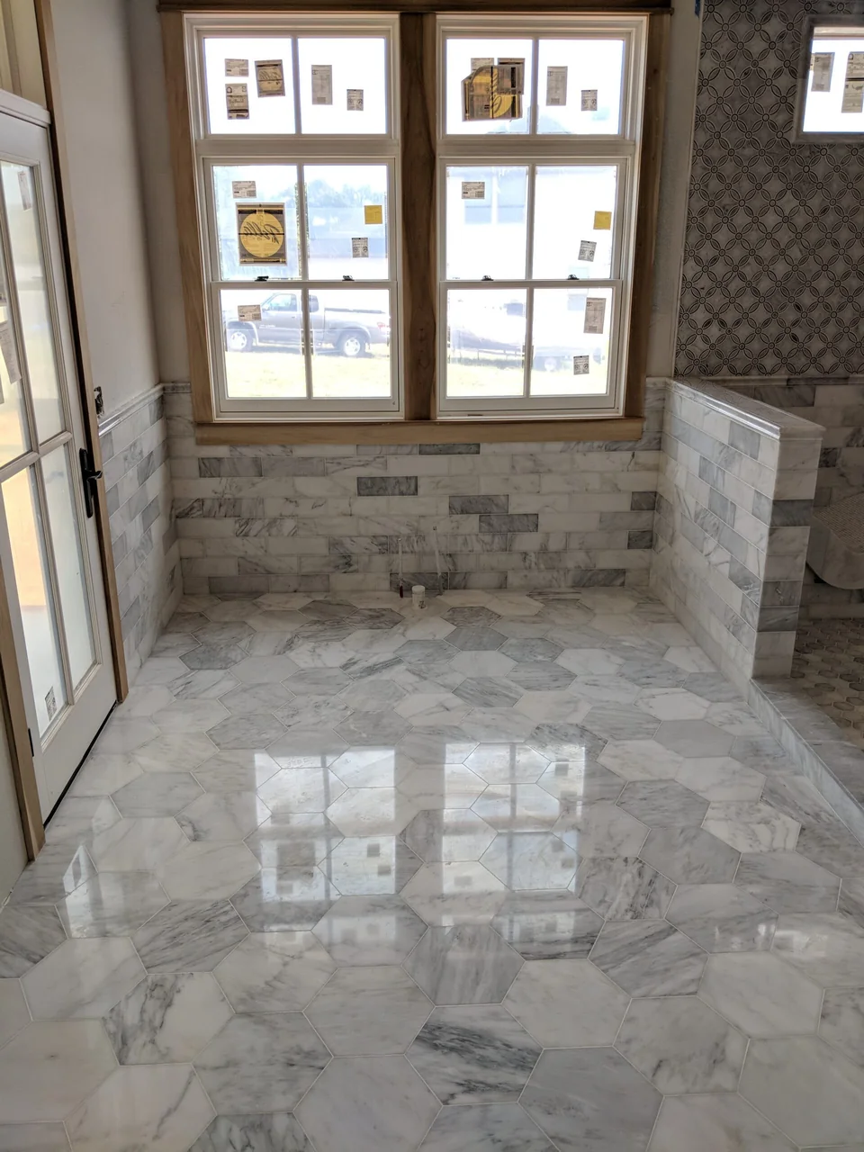 Polished stone floor leading into a patterned tile shower