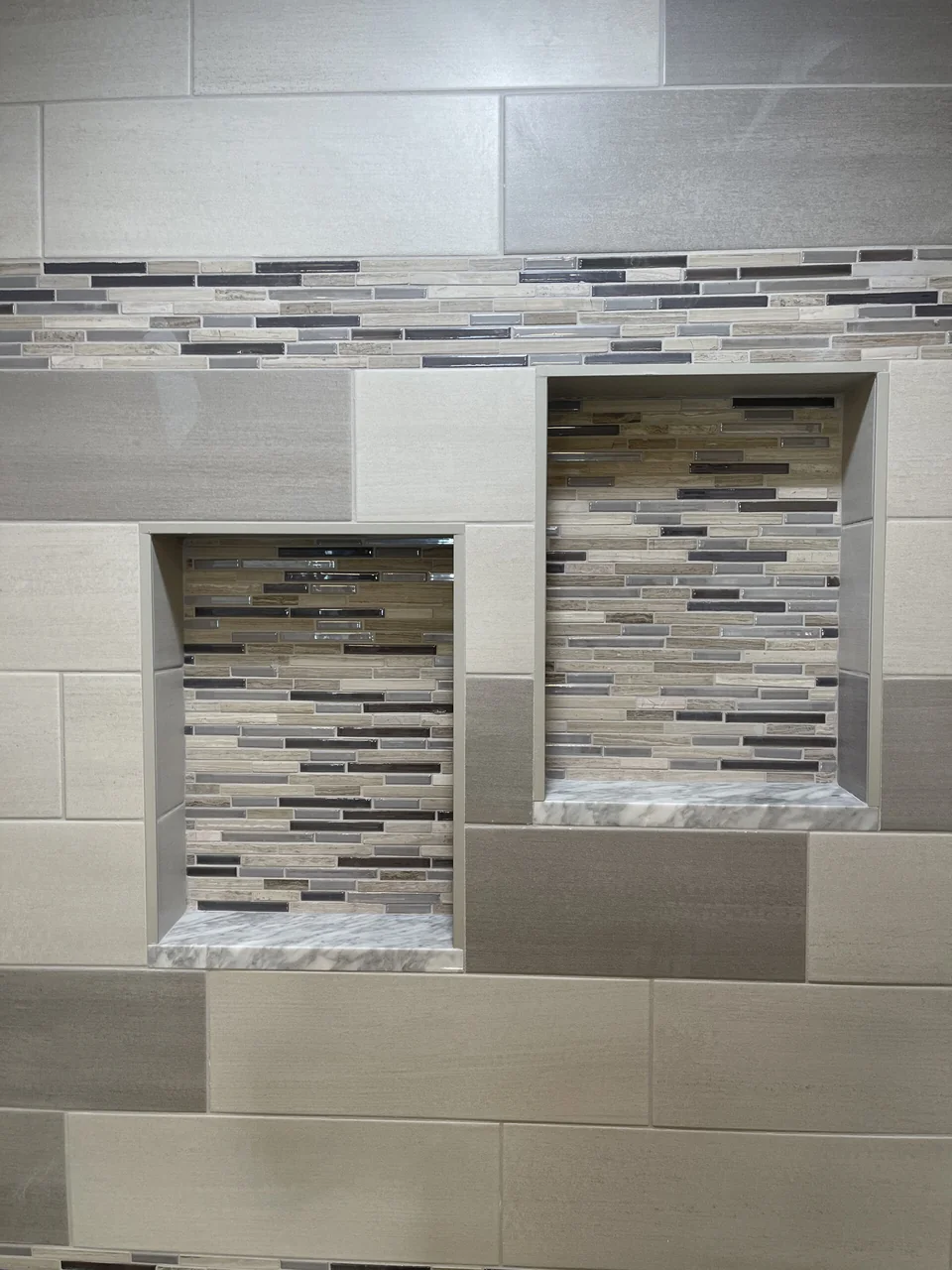 Two recessed shower niches with mosaic tile