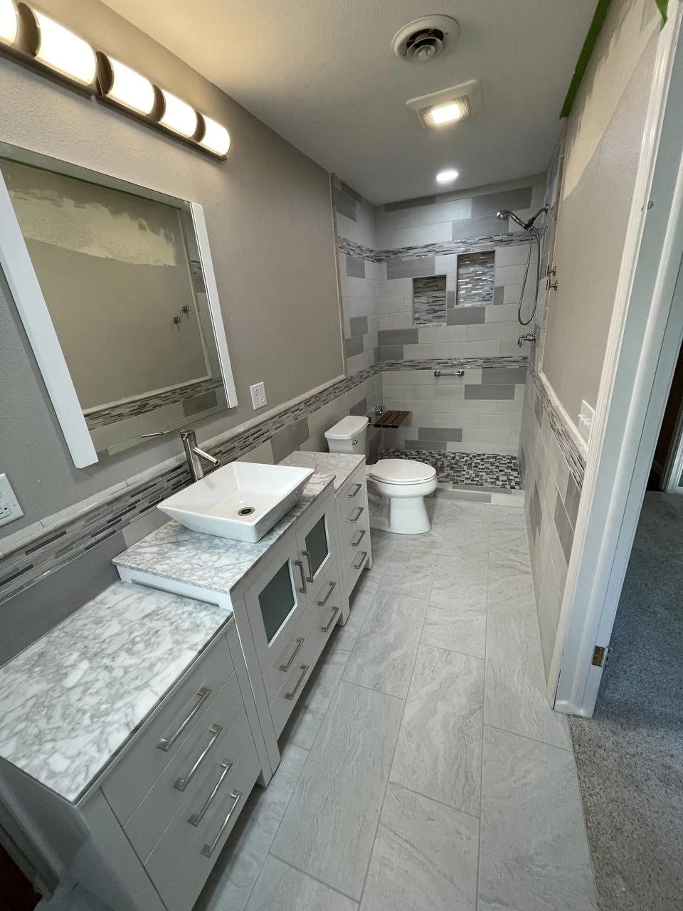 Bathroom vanity and mirror beside the tiled shower
