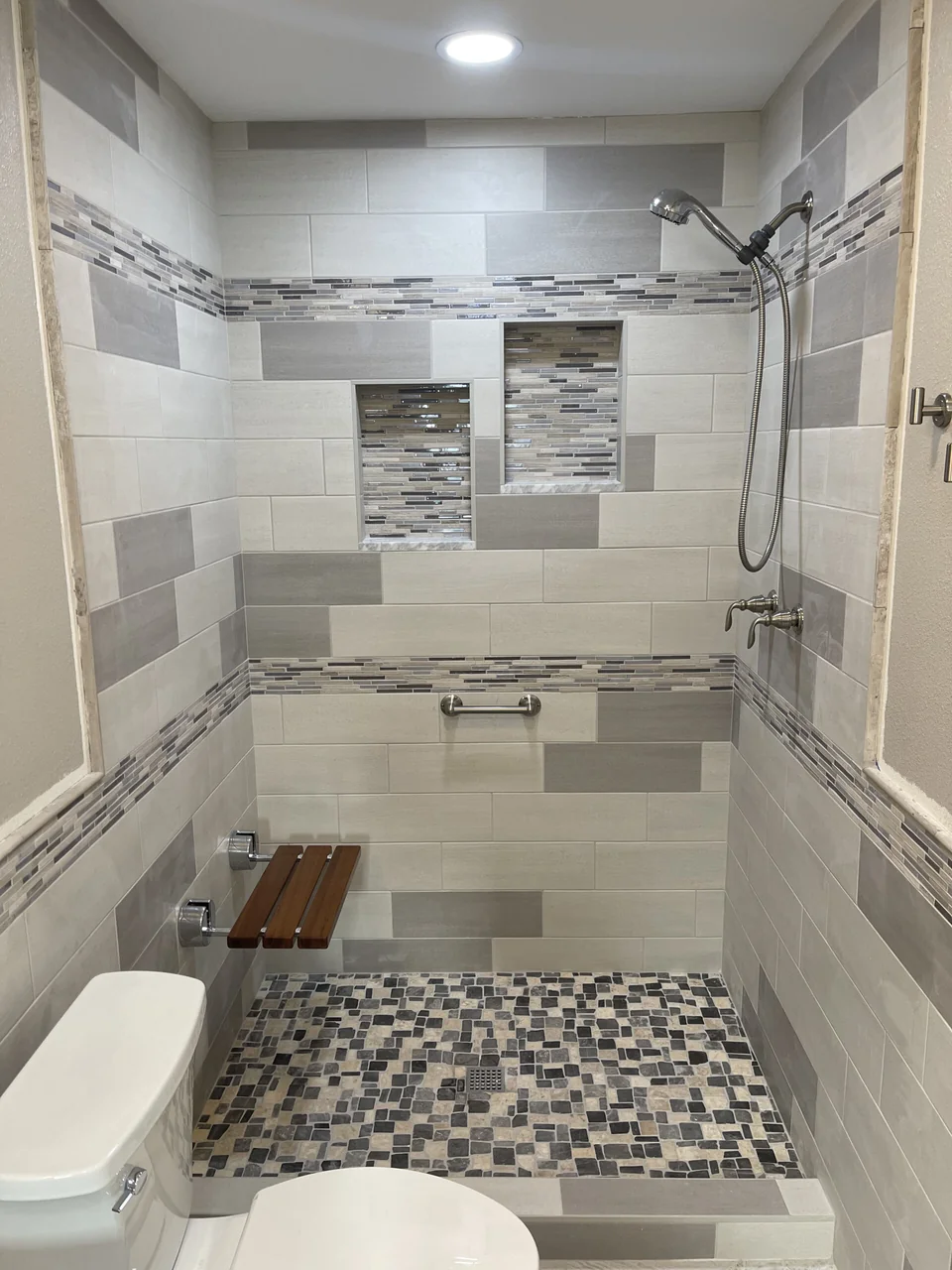 Custom tiled shower with mosaic floor and recessed niches