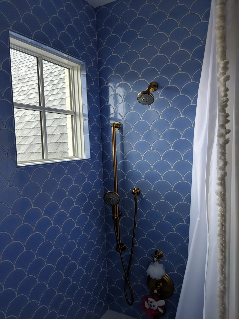 Blue scallop tile surrounding a shower window