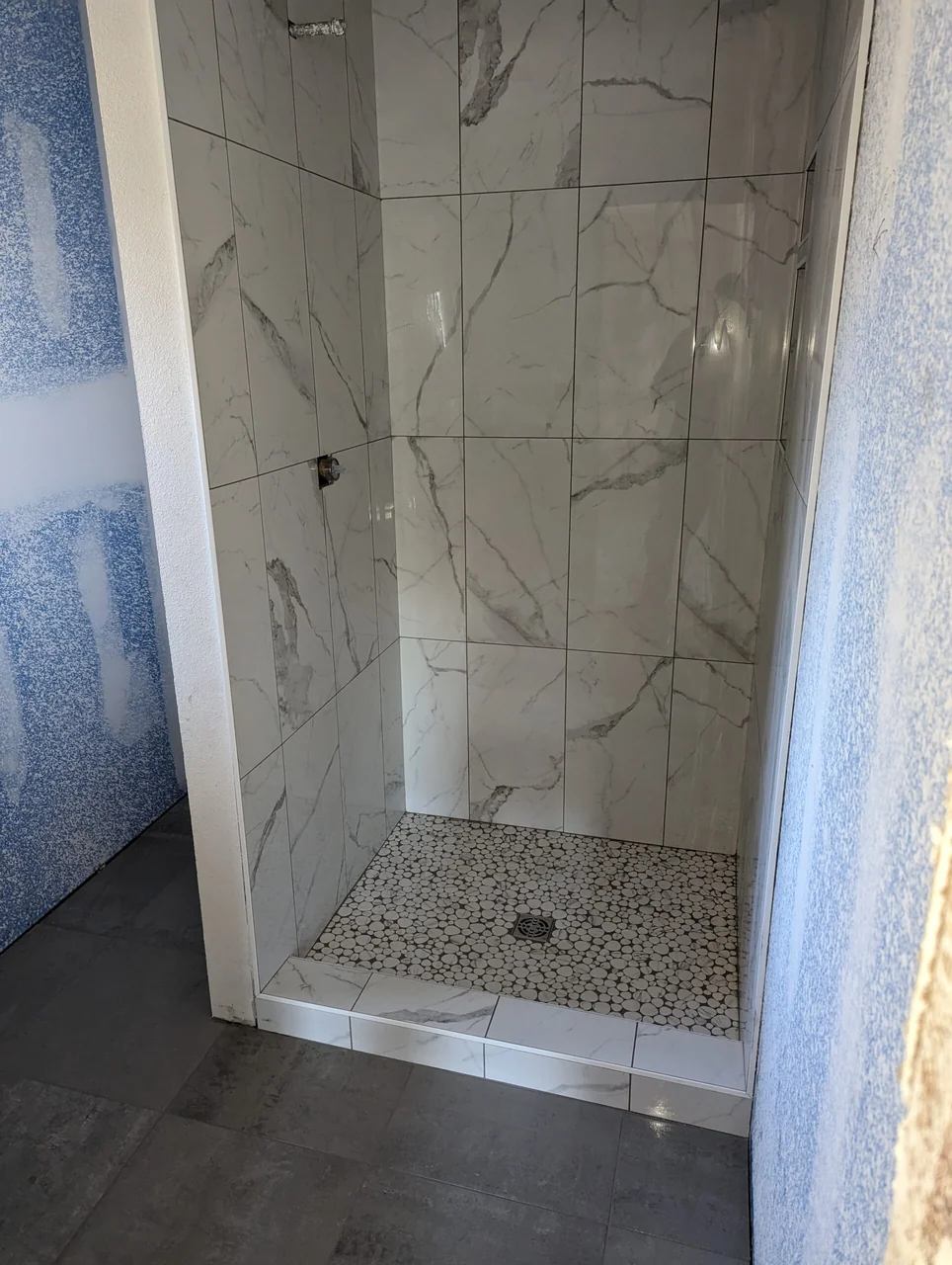 Veined tile shower with contrasting mosaic floor