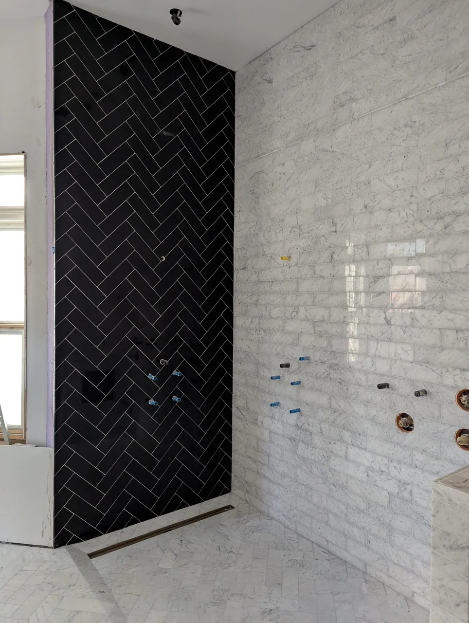 Black herringbone feature wall beside pale shower tile