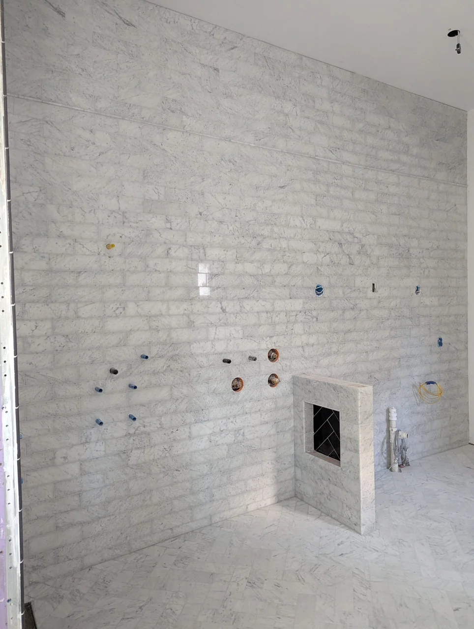 Pale wall tile around plumbing and a recessed niche