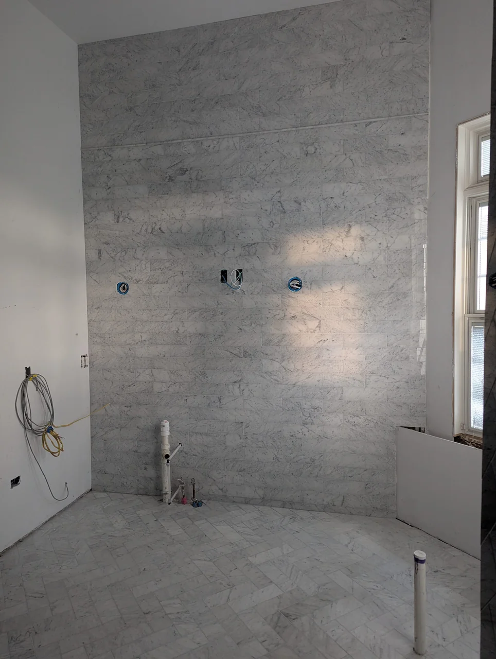 Tiled bathroom wall with plumbing openings