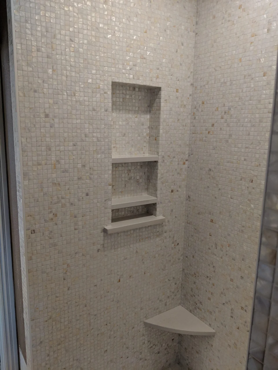 Recessed niches and corner seat in a mosaic shower