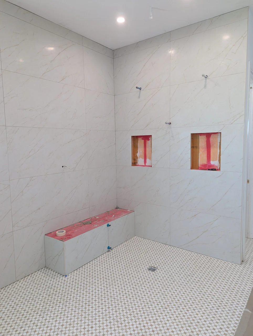 White tiled shower with a bench during installation