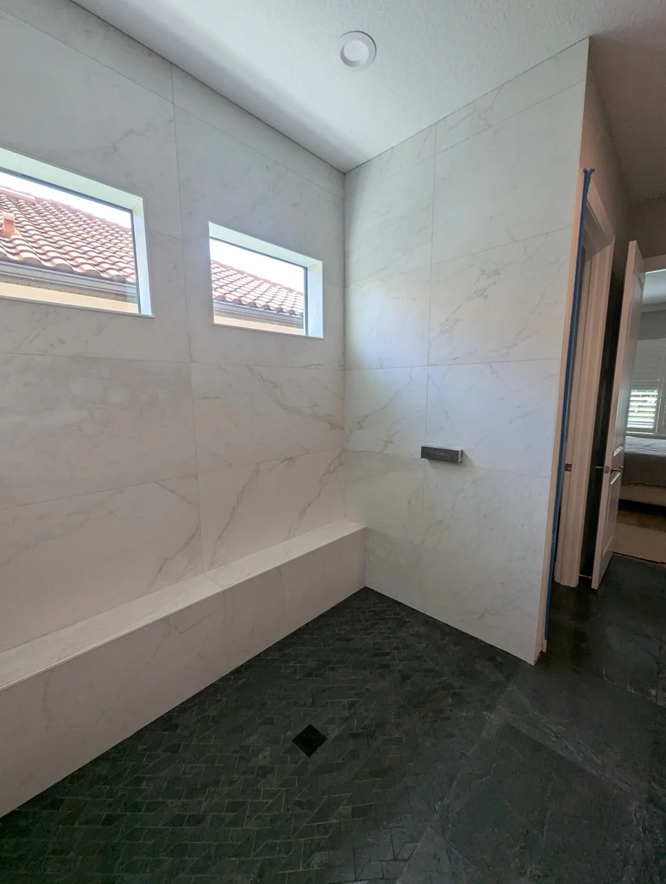 Pale stone-look shower walls and a floating bench