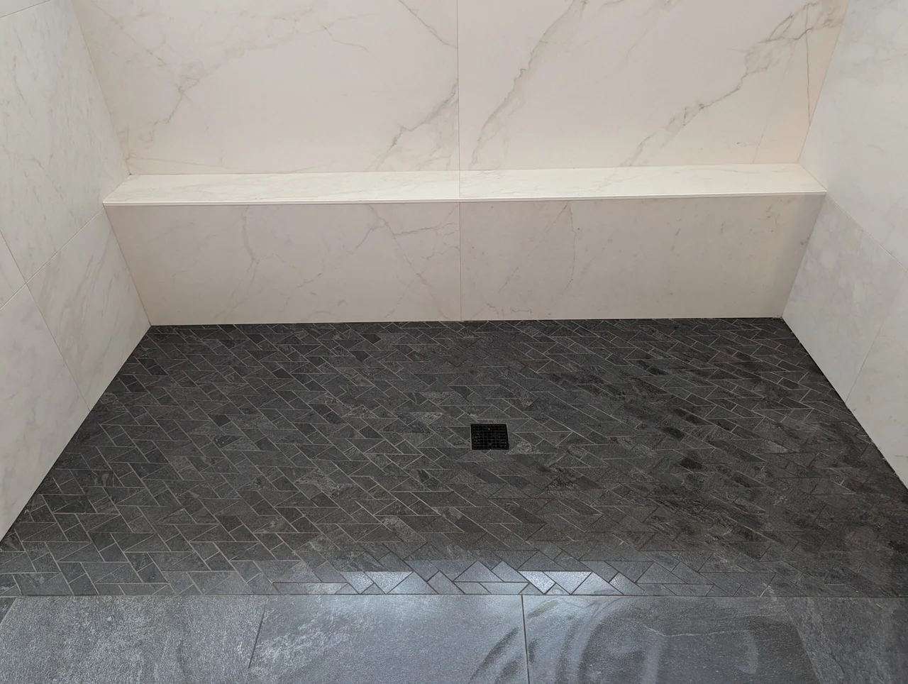 Dark shower floor below a floating bench