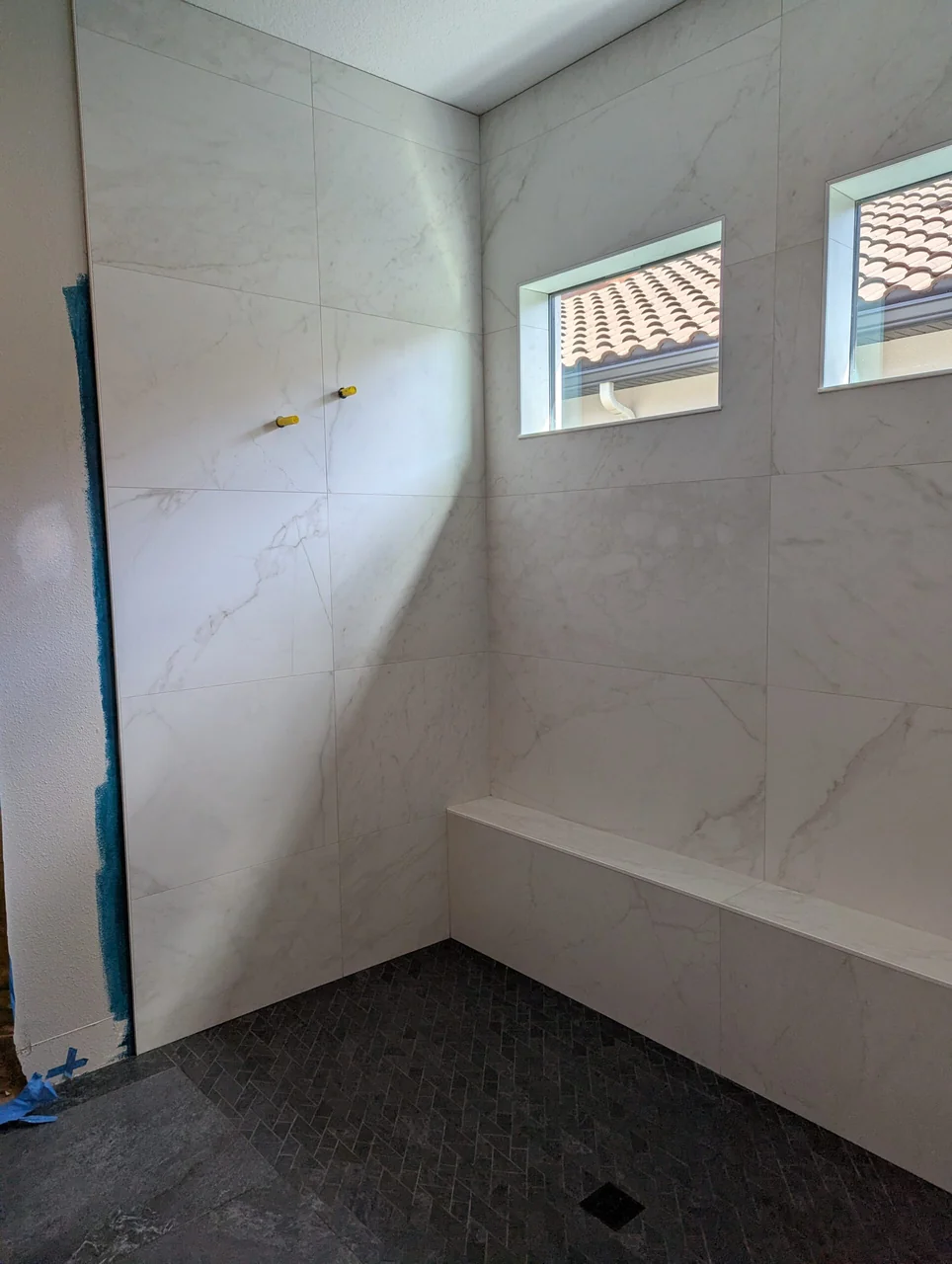 Walk-in shower with pale walls and dark floor